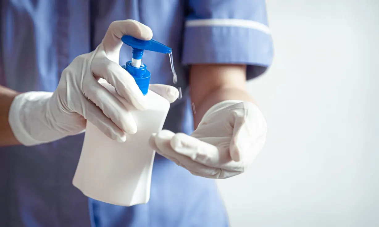 Medicinsko osoblje u rukavicama koristi dezinfekciono sredstvo